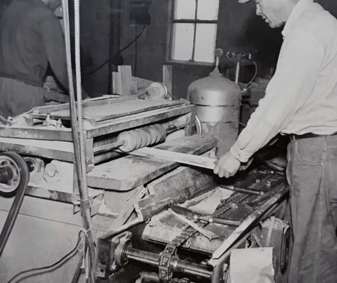 Old photograph of man building greenhouse flats out of wood.